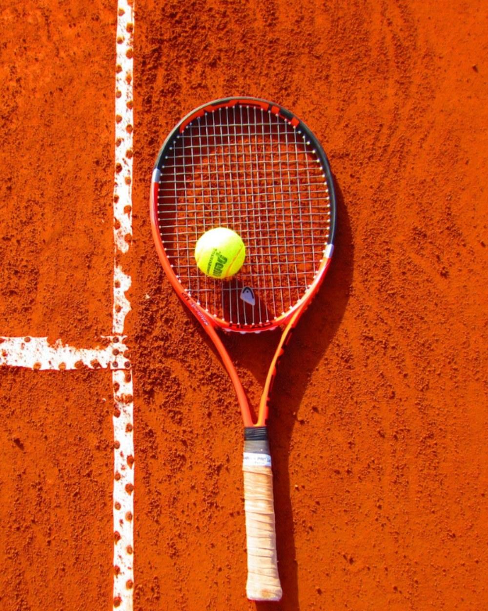 Raqueta y pelota sobre una cancha de arcilla